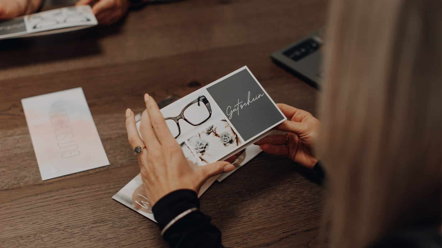 Blickfelder Gruppe und Betriebsgesellschaft: Augenoptikermeister zeigt Kundin neue Brillenfassung
